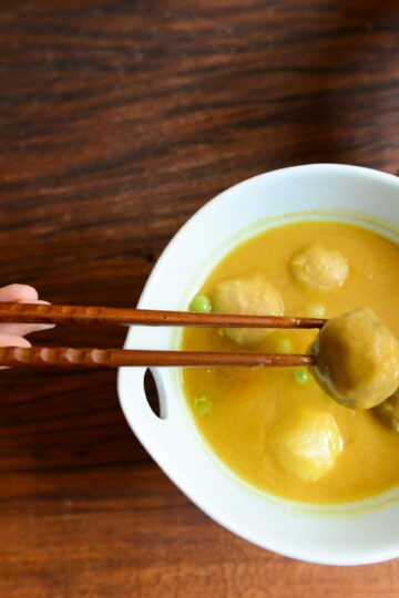 person holding chopsticks and white ceramic bowl